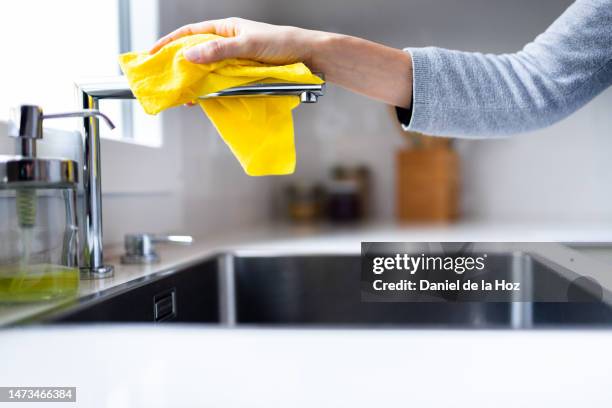 unrecognizable woman cleaning kitchen faucet with yellow cleaning cloth. copy space. hygiene and house chores - trapo de limpiar el polvo fotografías e imágenes de stock