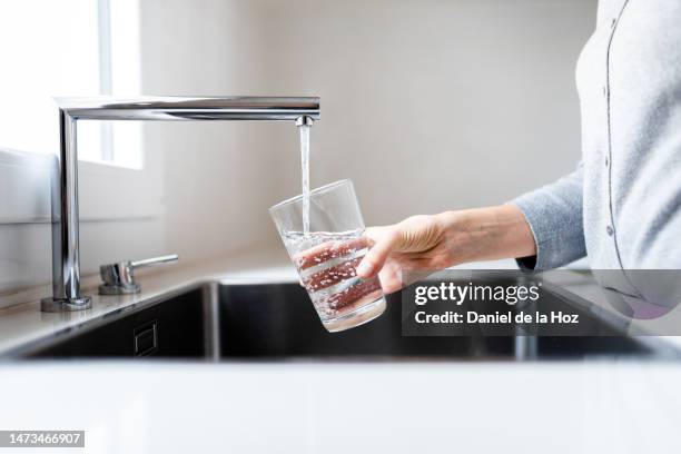 unrecognizable thirsty woman filling drinking glass with water to drink. stay hydrated. - water faucet stock pictures, royalty-free photos & images