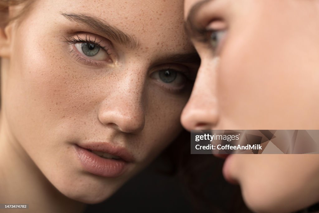 Beautiful emotional woman with natural make-up looking at the mirror