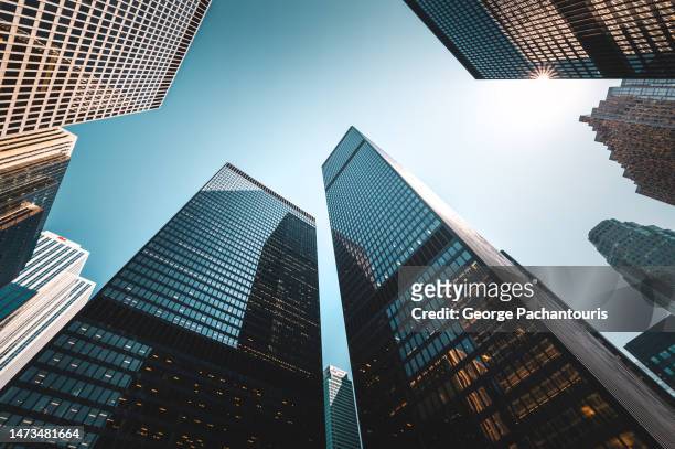 low angle view of sunlight and skyscrapers in the financial district - banque photos et images de collection