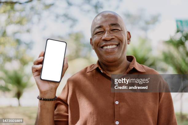 homem maduro segurando o smartphone - showing - fotografias e filmes do acervo