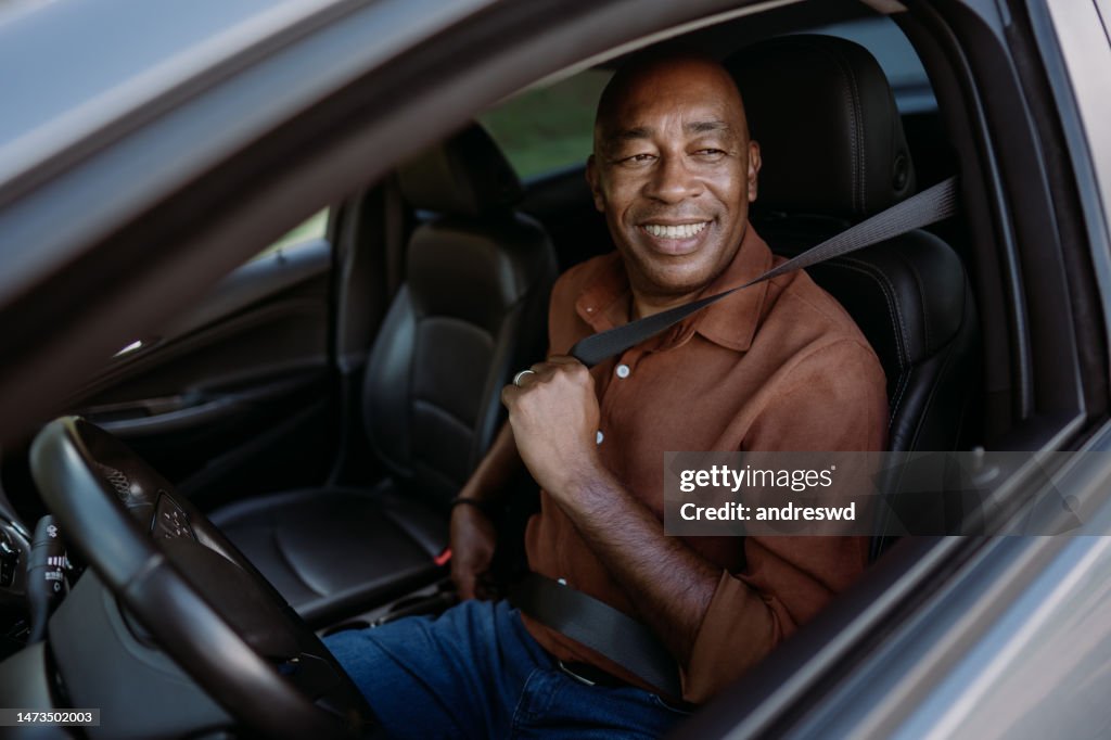 Motorista do sexo masculino que coloca o assento de segurança no carro