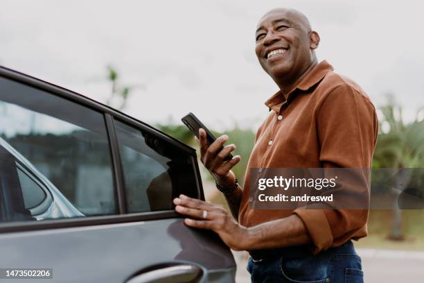 man getting into car holding smartphone - people in car stockfoto's en -beelden