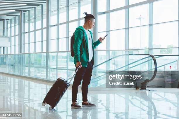 young man using smart phone at the airport - airport phone stock pictures, royalty-free photos & images