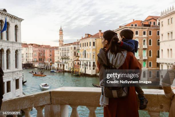 mother and son sightsee venice from grand canal bridge - gondola traditional boat stockfoto's en -beelden