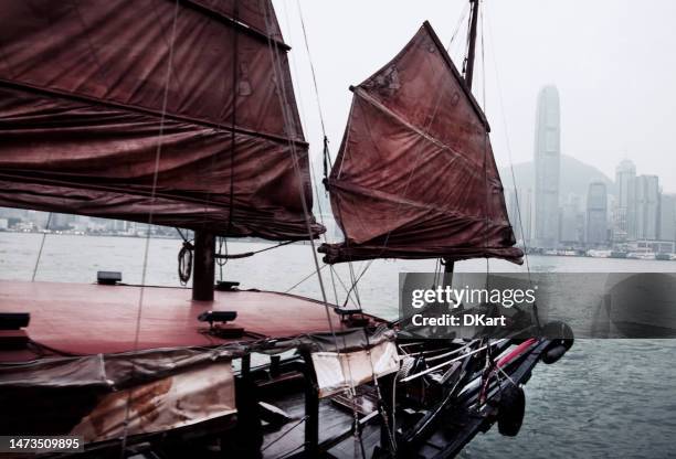 traditionelles trödelboot mit rotem segel vor dem hintergrund des hafens auf victoria island in hongkong - hong kong junk boat stock-fotos und bilder