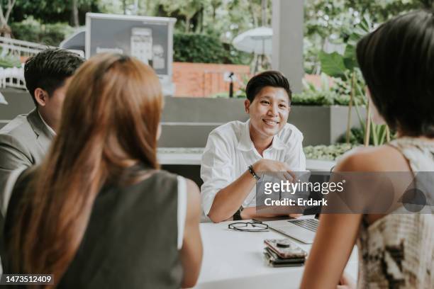 porträt eines asiatischen nicht-binären gender-beamten, der sich mit einem kollegen im café ausruht - small business meeting in asia stock-fotos und bilder