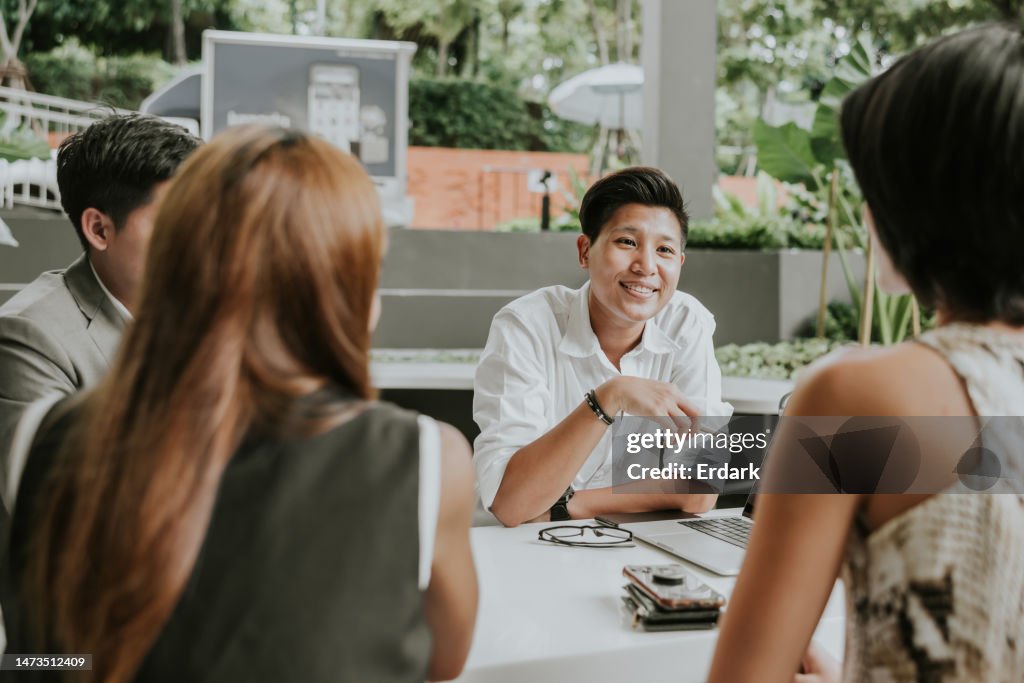 Portrait of Asian non binary gender officer while resting at cafe with colleague