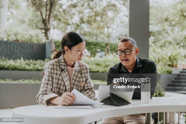 thai manager is giving an advice and explaining about work to his secretary. - business talk stock pictures, royalty-free photos & images