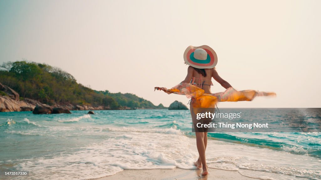 Sexy bikini body woman playful on paradise tropical beach having fun playing splashing water in freedom.