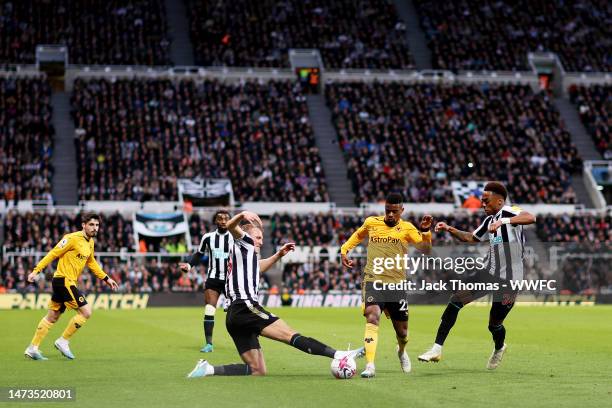 Nelson Semedo of Wolverhampton Wanderers is challenged by Dan Burn and Joe Willock of Newcastle United during the Premier League match between...