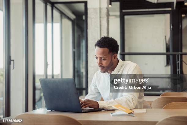 joven trabajando en una oficina - usar el ordenador fotografías e imágenes de stock