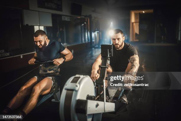 young athletic people having training on rowing machines and bycicles in a health club - rowing machine stock pictures, royalty-free photos & images