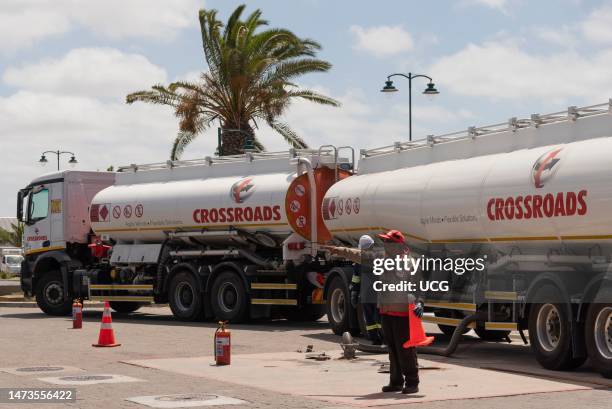 Langebaan, Western Cape, South Africa, Worker directing the unloading of fuel from a petrol tanker and trailer at a garage in Langebaan, South Africa.