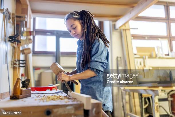 mujer carpintera tallando madera con herramientas en taller - mazo fotografías e imágenes de stock