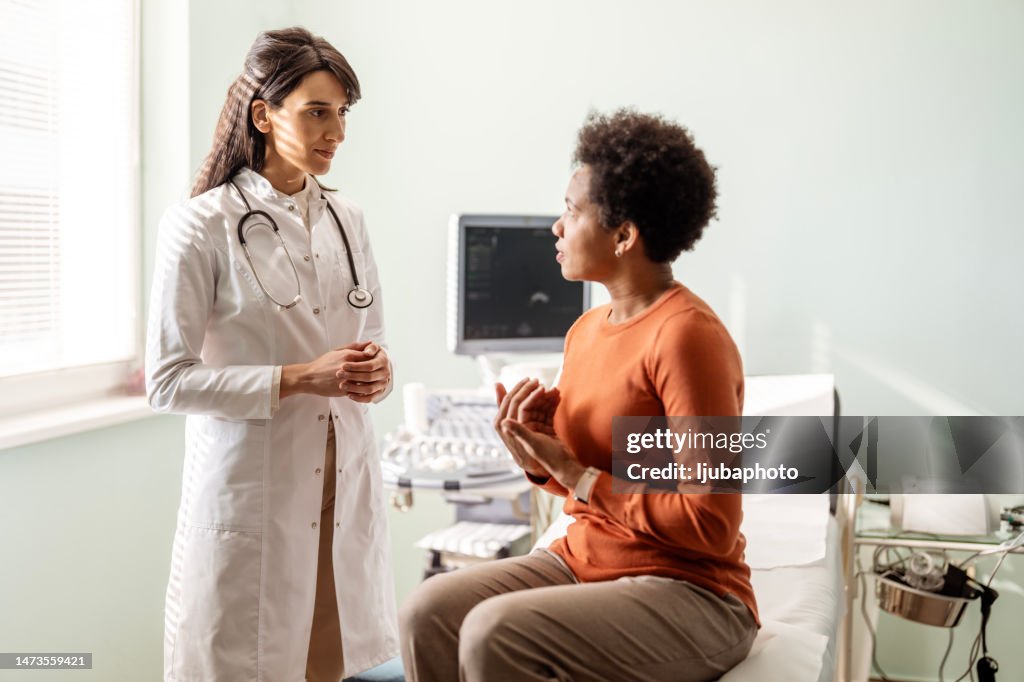 Eine Ärztin spricht mit ihrer Patientin vor ihr, während sie über ihre Bedenken sprechen.