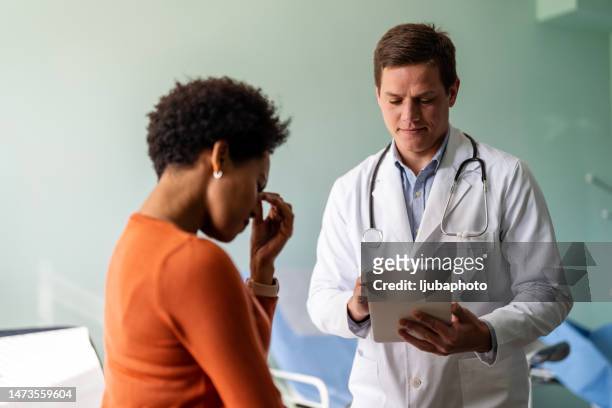 doctor talking to unhappy female patient in exam room - surprised woman looking at tablet stock pictures, royalty-free photos & images