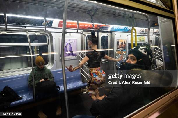 Aerialist Erin Blaire performs hair hanging tricks for a photographer and commuters while hanging from the overhead hand-rails on a subway car on...