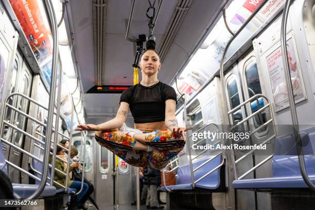 Aerialist Erin Blaire performs hair hanging tricks for a photographer and commuters while hanging from the overhead hand-rails on a subway car on...