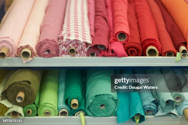 rolls of different coloured material in a textile store - fabric rolls photos et images de collection