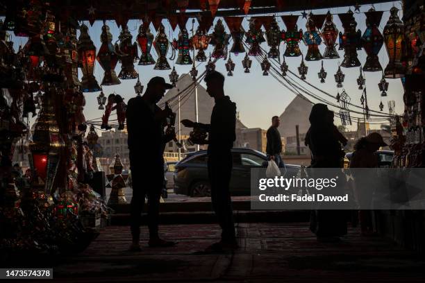 People buy traditional lanterns of the holy Muslim month of Ramadan at a market shop in the central El-Haram district on March 14, 2023 in Cairo,...
