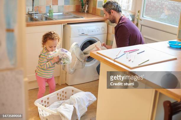 dad and daughter loading the washing machine - man washing basket child stock pictures, royalty-free photos & images