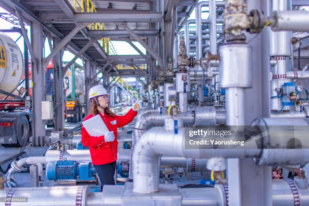 Female petrochemical inspector working on site,checking the industrial equipment