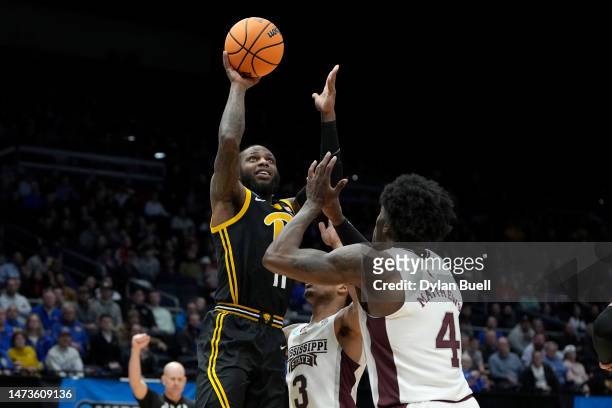 Jamarius Burton of the Pittsburgh Panthers shoots the ball against Shakeel Moore and Cameron Matthews of the Mississippi State Bulldogs during the...
