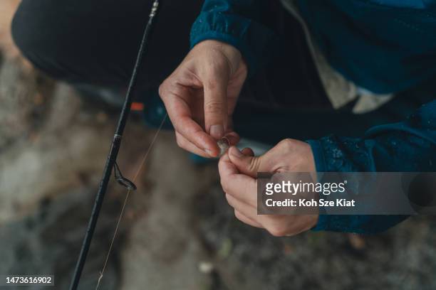 upclose pf an asian chinese woman hands tying fishing line - fishing bait stock pictures, royalty-free photos & images