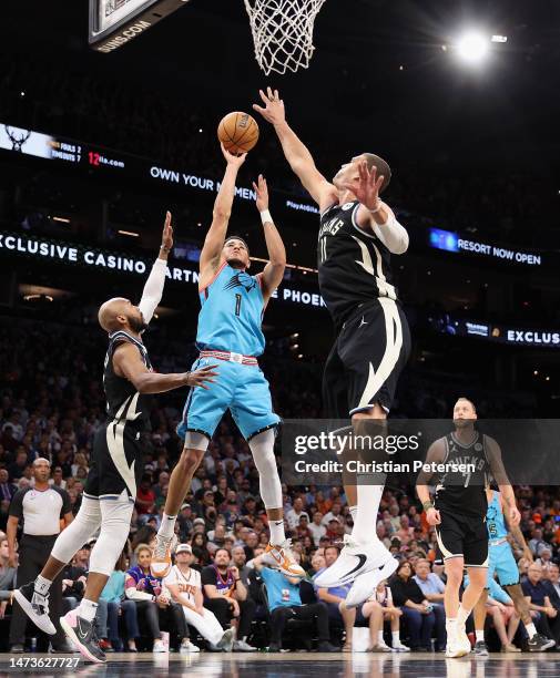 Devin Booker of the Phoenix Suns puts up a shot against Jevon Carter and Brook Lopez of the Milwaukee Bucks during the first half of the NBA game at...