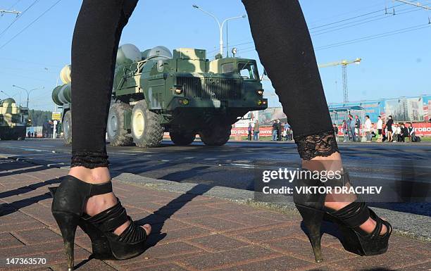 Partly seen girl stands on a pavement as a column of Belarussian Army S-300 air-defense missile launchers rolls in central Minsk, on June 28 during a...