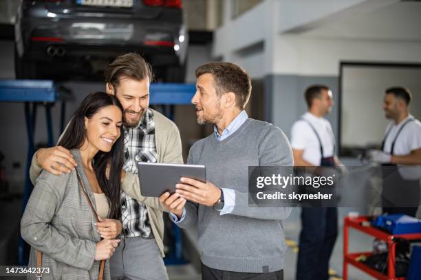 mid adult manager and young couple using touchpad in auto repair shop. - touchpad stockfoto's en -beelden