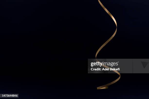 sparkling gold colored metallic glitter ribbon on black background - or fond noir photos et images de collection