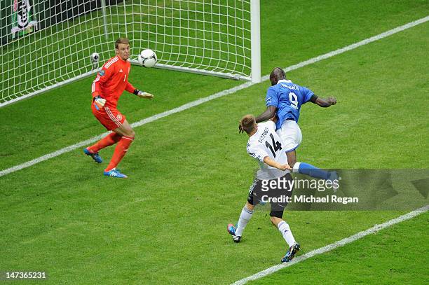 Mario Balotelli of Italy jumps next to Holger Badstuber of Germany to score the opening goal past Manuel Neuer of Germany during the UEFA EURO 2012...