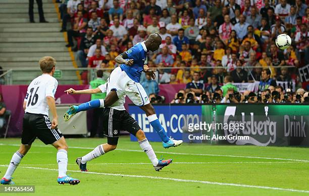 Mario Balotelli of Italy jumps next to Holger Badstuber of Germany to score the opening goal during the UEFA EURO 2012 semi final match between...