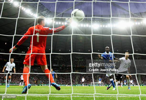 Mario Balotelli of Italy jumps next to Holger Badstuber of Germany to score the opening goal past Manuel Neuer of Germany during the UEFA EURO 2012...