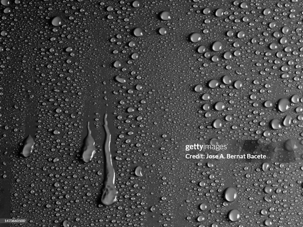Drops of water sliding down a black surface.