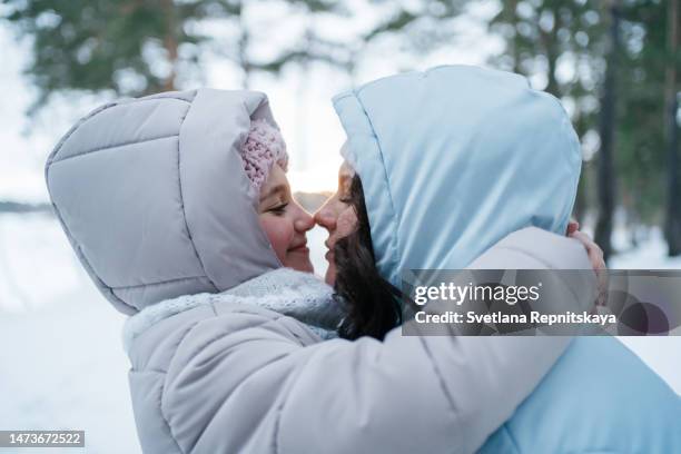 mother hugging daughter in snowy forest - kapstaden stockfoto's en -beelden