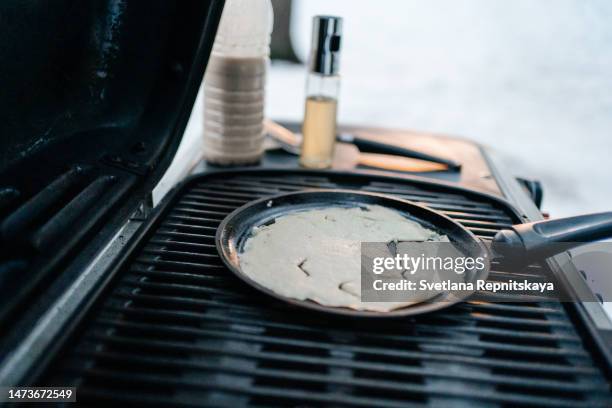 man fries pancakes on a gas grill in a snowy forest in the spring picnic - fireplace wood basket stock pictures, royalty-free photos & images