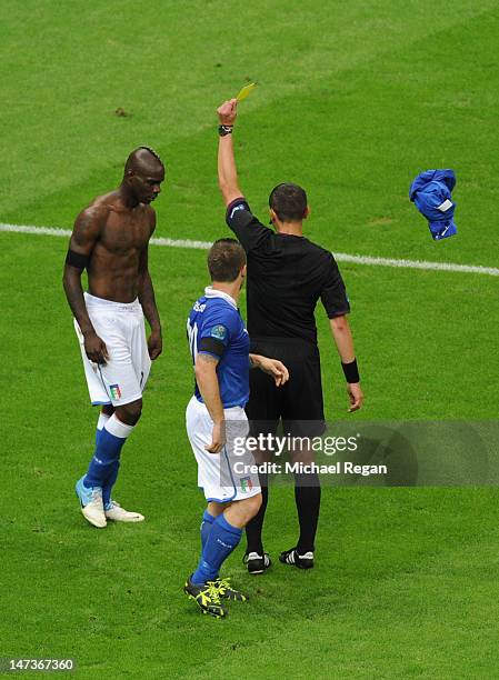 Referee Stephane Lannoy shows Mario Balotelli of Italy a yellow card after he removed his shirt during celebrations following his second goal during...