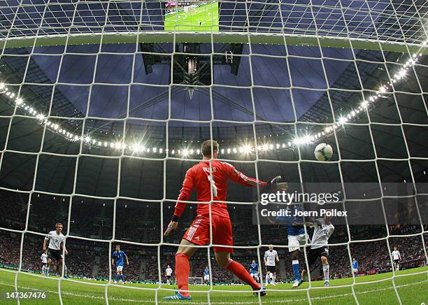 Mario Balotelli of Italy jumps with Holger Badstuber of Germany to score the opening goal past Manuel Neuer of Germany during the UEFA EURO 2012 semi...