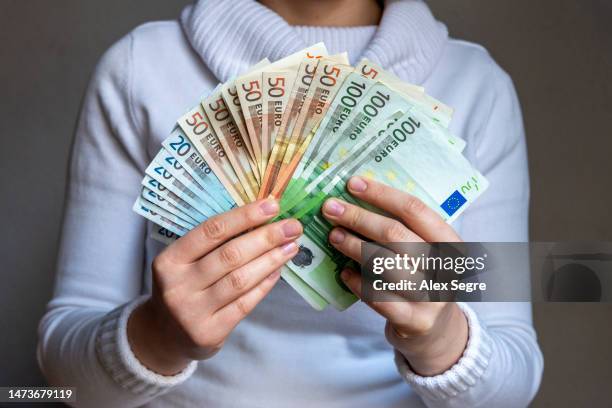 hand holding bundle of euro banknotes - fajo de billetes de euro fotografías e imágenes de stock