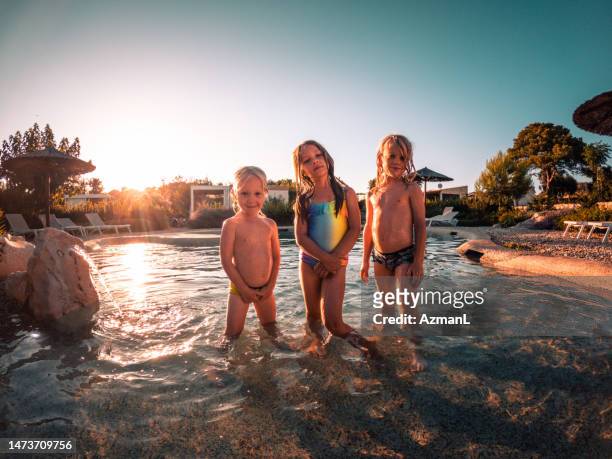 sunset shot of siblings standing by hotel pool - blonde hair boy stock pictures, royalty-free photos & images