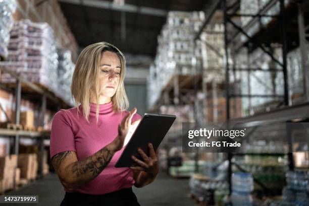 mature woman working on a digital tablet in a warehouse - shipping stock pictures, royalty-free photos & images