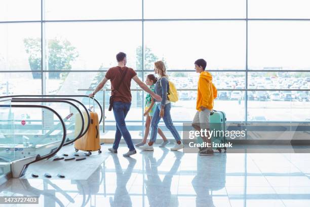 family with luggage walking at airport - airport departure area stock pictures, royalty-free photos & images