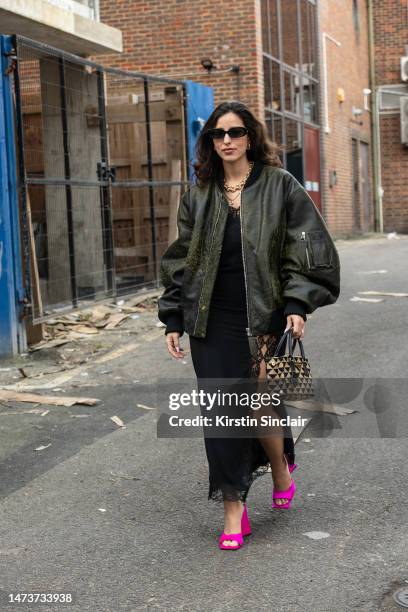 Bettina Looney wears Linda Farrow sunglasses, The Attico shoes and jacket, Prada bag and a Christopher Kane dress outside the Christopher Kane show...