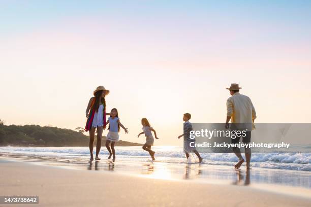 on a beach, a family walks and runs together on a summer day. - boy and girl running along beach holding hands stock-fotos und bilder