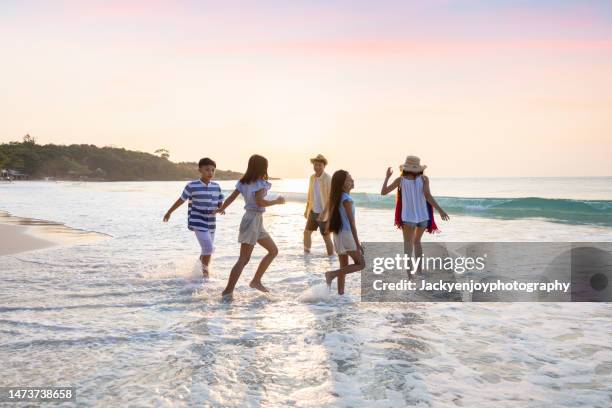 on a beach, a family walks and runs together on a summer day. - couple sand sunset stock pictures, royalty-free photos & images