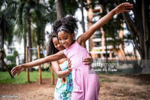 mãe ajudando filha a caminhar com equilíbrio em um parque - brincar - fotografias e filmes do acervo