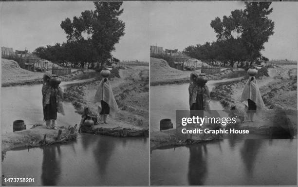 Stereoscopic image showing women collecting water from the acequia, in the pueblo of San Juan, San Juan County, New Mexico, circa 1885. Published as...